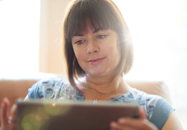 istock Mature woman browsing the internet on a digital tablet 512115524