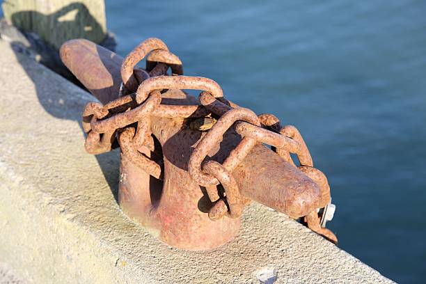 Cleat with a metal chain attached to it at a wharf.