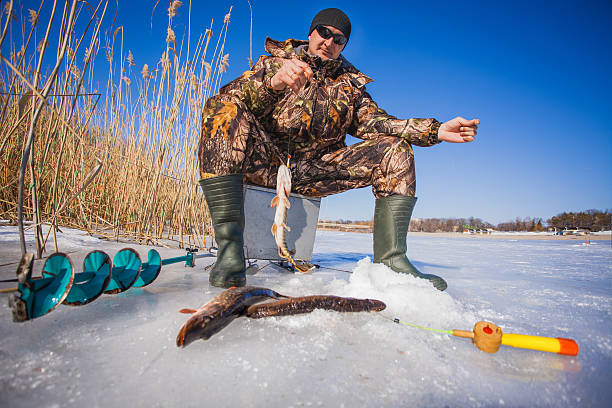 ice fisherman with pike caught on a tip up Happy ice fisherman holding a pike caught on a tip up man ice fishing stock pictures, royalty-free photos & images