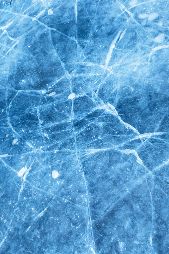 A network of cracks on a piece of blue ice with air bubble.