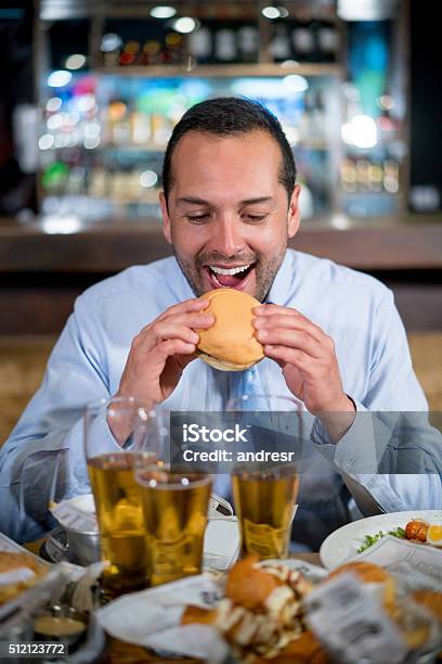 Man Eating A Burger At A Bar Stock Photo - Download Image Now - Adult, Adults Only, Bar - Drink Establishment