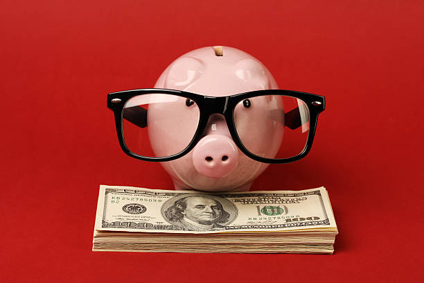istock Piggy bank with glasses standing on stack of money 512125218