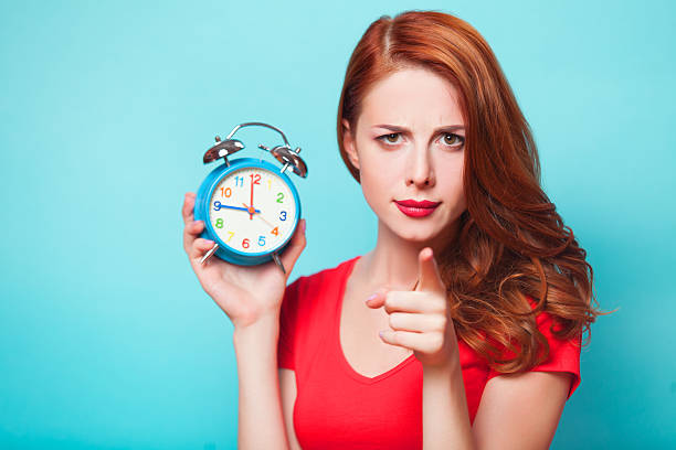 istock Redhead girl with alarm clock on blue background. 512127813