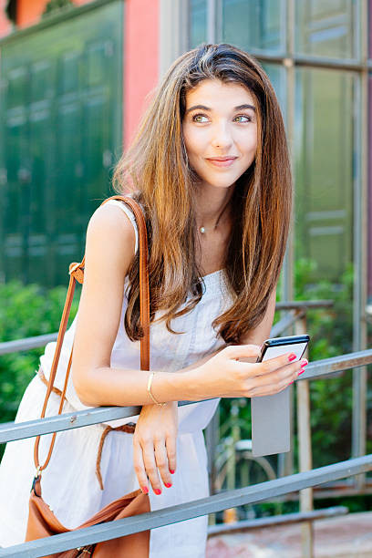 istock Happy and dreamy girl using her mobile phone 512129589