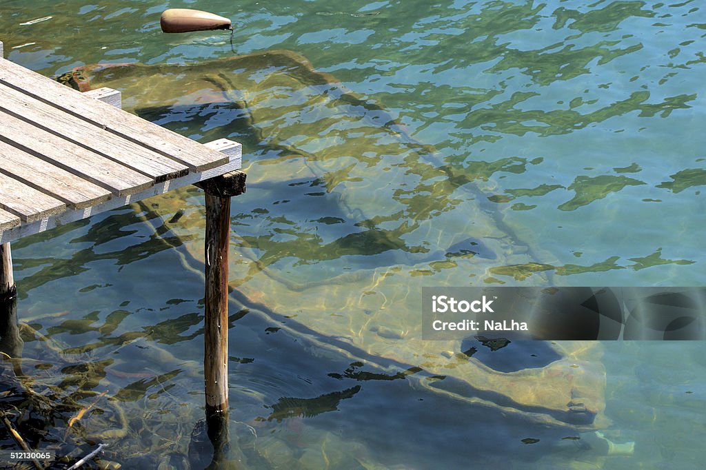 Old rowing boat under water at a wooden jetty Old rowing boat sunken under water at a wooden jetty Leaking Stock Photo
