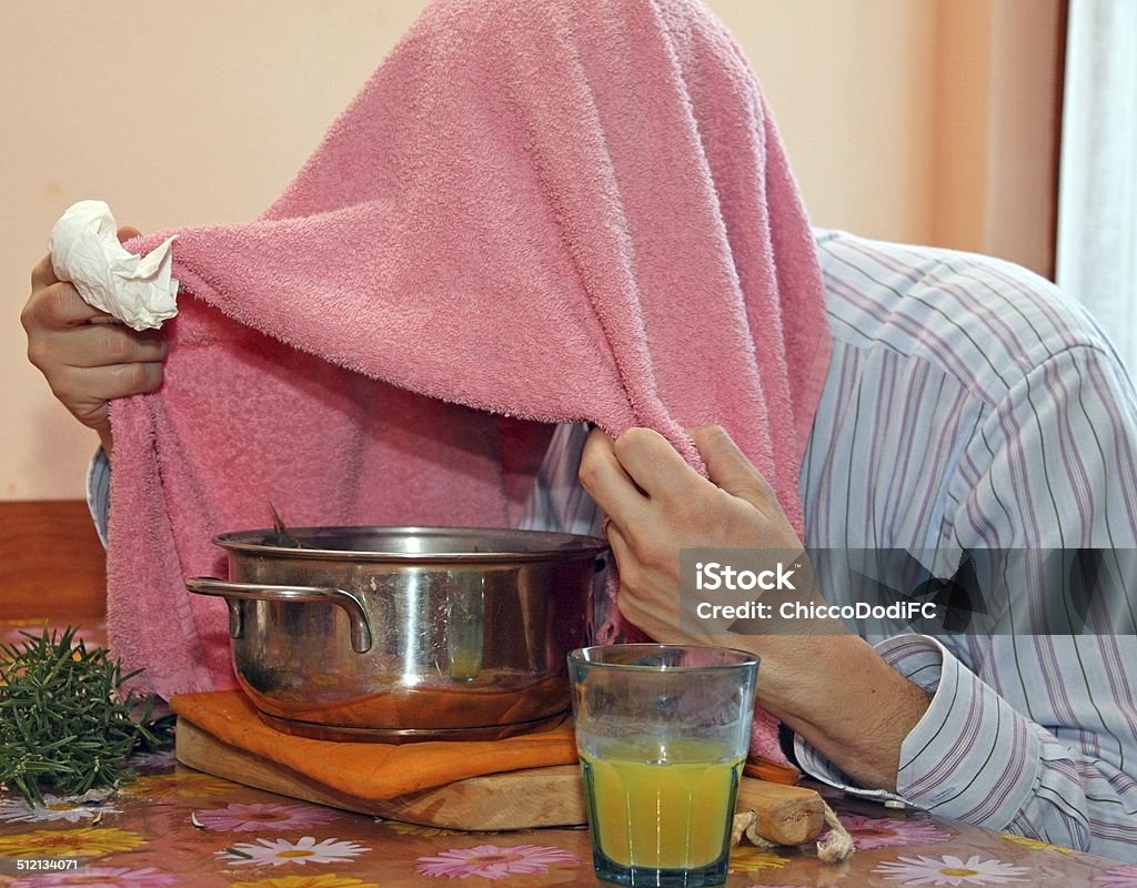 man with towel breathe balsam vapors to treat colds man with towel breathe balsam vapors to treat colds and the flu and a glass of orange juice Adult Stock Photo