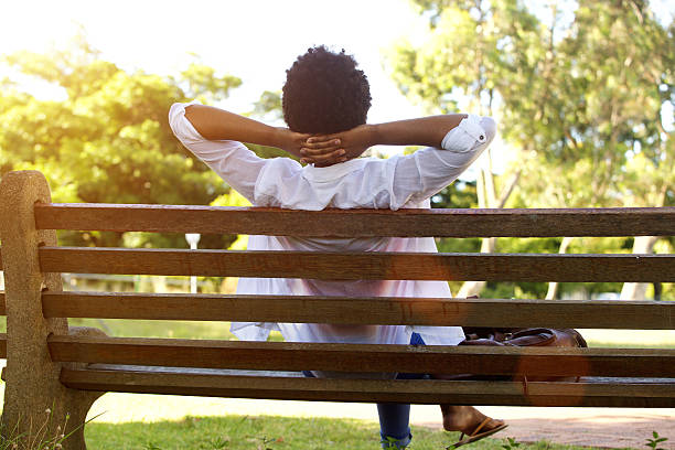 istock Young lady sitting relaxed on a park bench 512142254