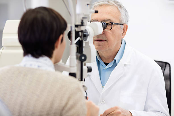 istock Senior eye specialist look in ophthalmoscope and perform eye rev 512142982