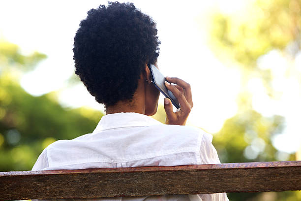Woman sitting on park bench and talking on mobile phone