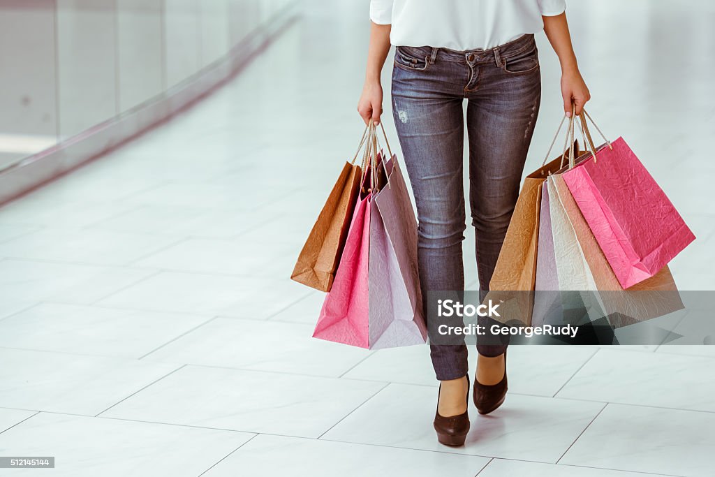 Woman doing shopping Beautiful young woman in white blouse and jeans holding shopping bags and doing shopping in mall, cropped Adult Stock Photo