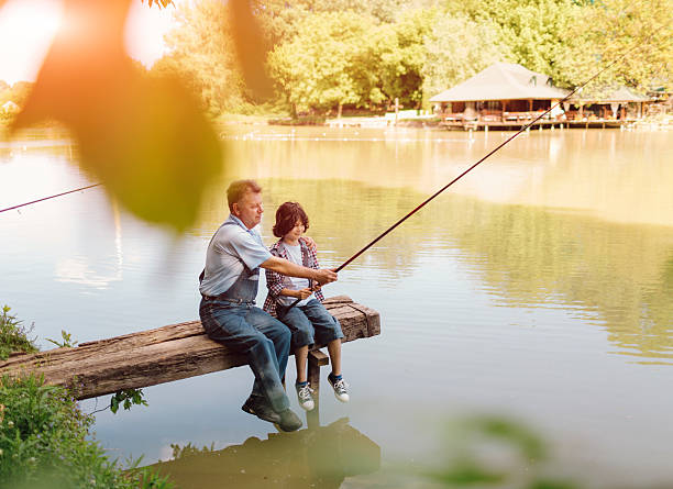 grandpa et petit-fils de pêche ensemble. - fishing lake grandfather grandson photos et images de collection