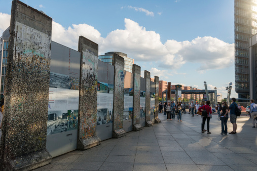 Berlin, Germany - August 12, 2014: tourists looking at the informations about the Berlin Wall, they read the history. Some pieces of the original Berlin Wall with graffity and between a lot of text and information about the history. Photo taken at the Potsdamer Platz Berlin, Germany