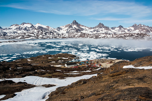 Fog spreads across the fjord at Tasiilaq, Greenland, with the town's rubbish dump on the shore.