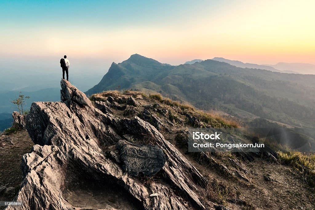 Hombre caminatas en el pico de la montaña de rocas al anochecer - Foto de stock de Montaña libre de derechos