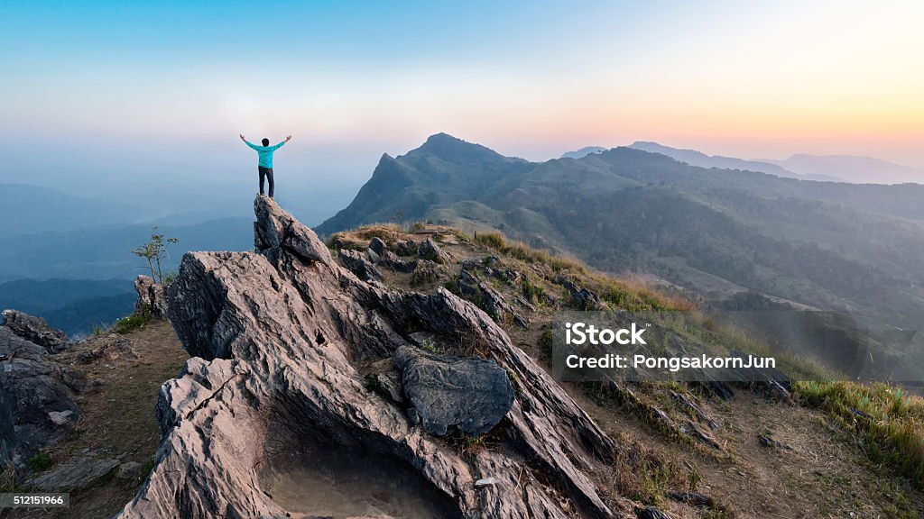 Hombre caminatas en el pico de la montaña de rocas al anochecer - Foto de stock de Montaña libre de derechos