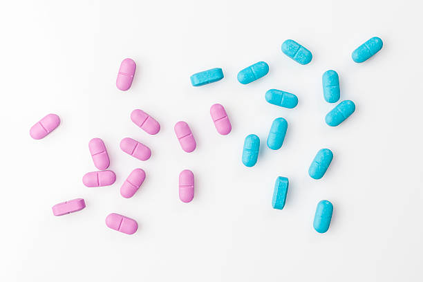 vereinzelt rosa und blauen pillen auf weiß von oben - pink pill stock-fotos und bilder