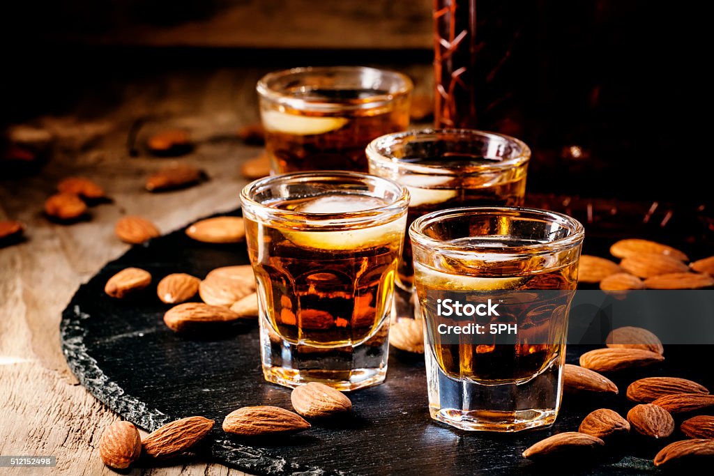 Brandy and almonds, small glasses Brandy and almonds, small glasses on a dark background, selective focus Amaretto Liqueur Stock Photo