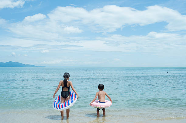 ragazzo e ragazza sulla spiaggia - wading child water sport clothing foto e immagini stock