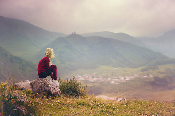 woman and mountain landscape relaxing woman  on  a stone enjoys the view vanishing point stock pictures, royalty-free photos & images