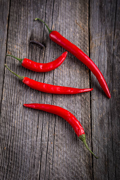 istock Four fresh red hot chilli peppers on old wooden table 512154204