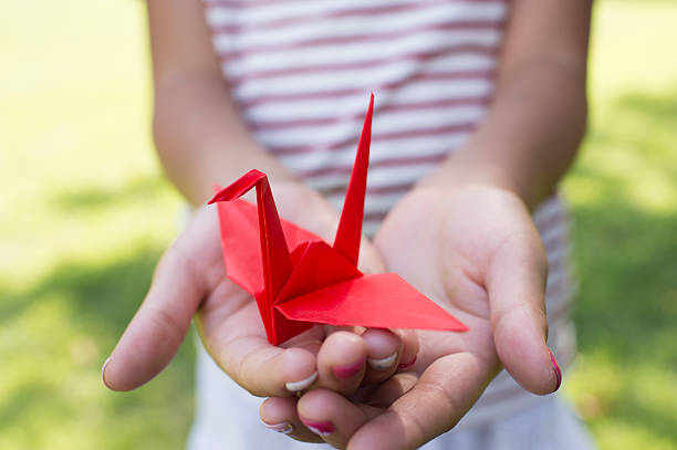 chica sosteniendo un grulla de papel - origami fotografías e imágenes de stock