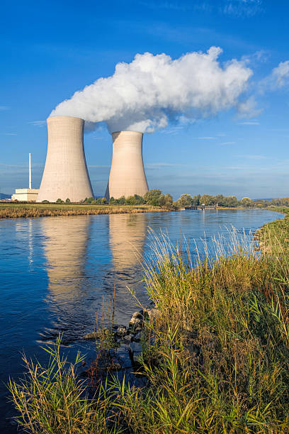 istock Nuclear power station with steaming cooling towers and blue sky 512155484
