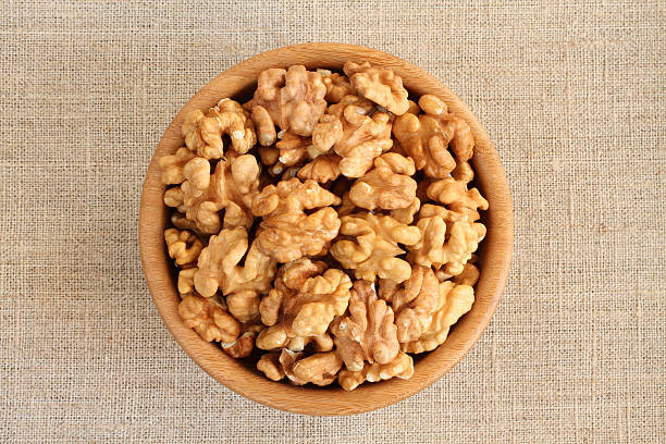 istock Big shelled walnuts in bamboo bowl on rough linen cloth 512156926