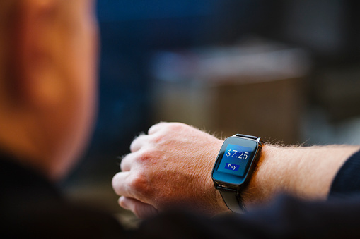 A man looks at his smart watch which is showing a prompt to make a small payment.