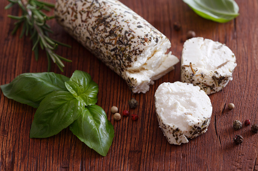 Goat cheese with fresh herbs on rustic table.