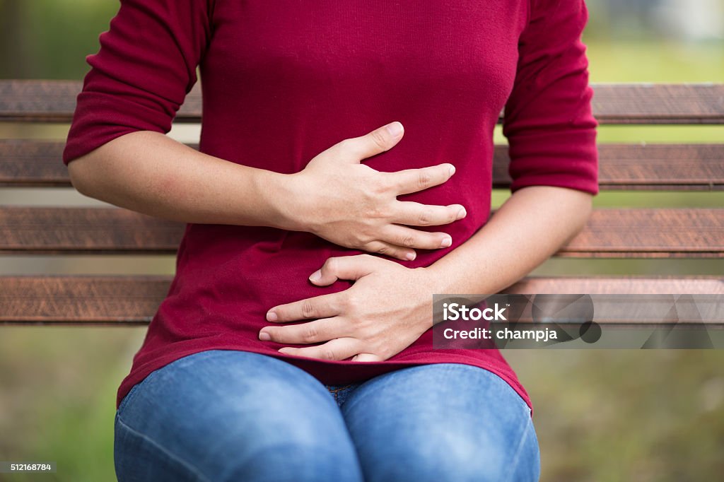 Woman Has Stomach Ache Sitting on Bench at Park Abdomen Stock Photo