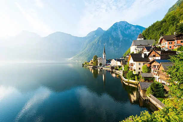 First of the early morning sunlight and mist fall on the lakeside village of Hallstatt, Austria.