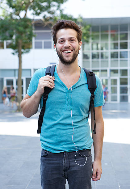 istock Young man standing with backpack and earphones 512176277