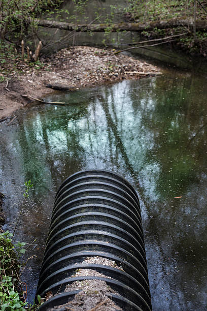 istock Dirty water stems from the pipe polluting the forest river 512183827