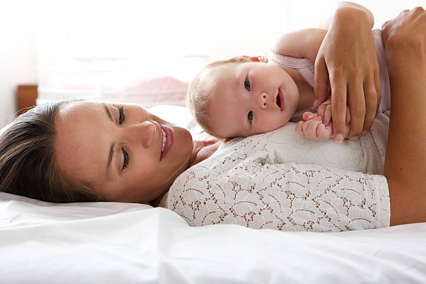 istock Loving mother resting with baby in bed 512184239