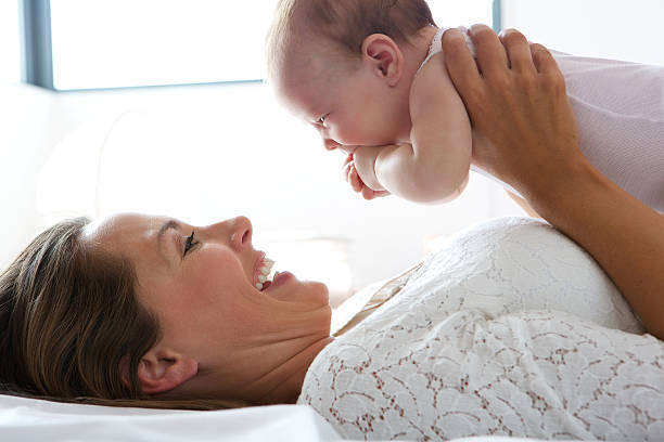 Happy mother holding cute baby in bed