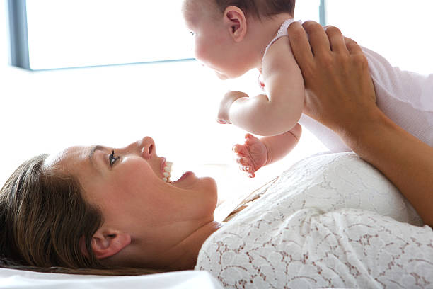 istock Smiling mother holding baby in bed 512184673