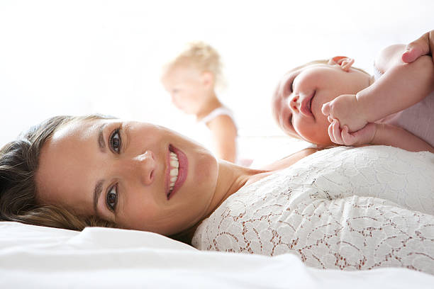 Beautiful mother smiling in bed with baby