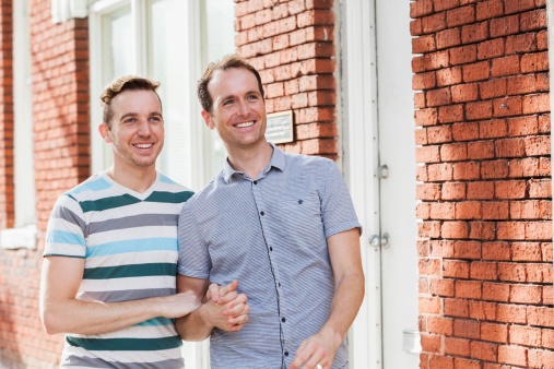 Gay couple (20s, 30s) walking, holding hands.