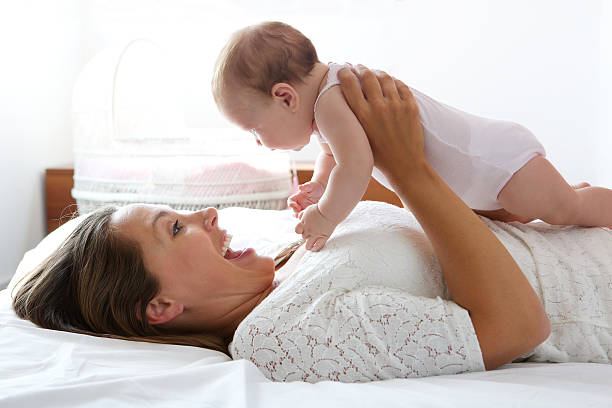 istock Happy mother playing with cute baby in bed 512185007