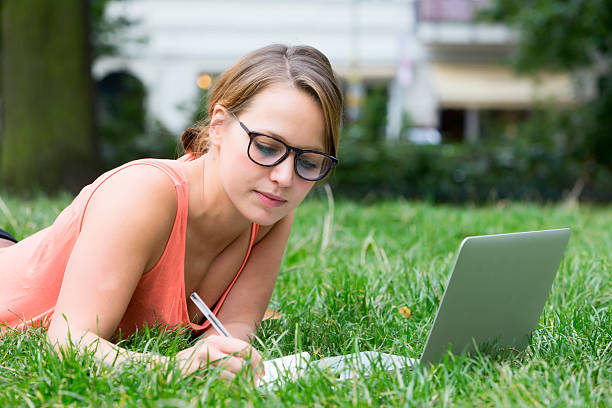istock Woman on the grass with computer and pen 512185575