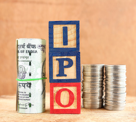 Initial public offering, or IPO, concept, indicated with wooden blocks with letters forming the word IPO and Indian rupees and stack of coins.