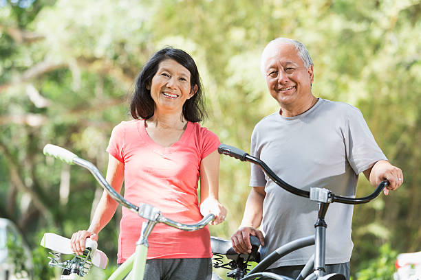 asiático casal equitação bicicletas - action mature adult bicycle senior couple imagens e fotografias de stock