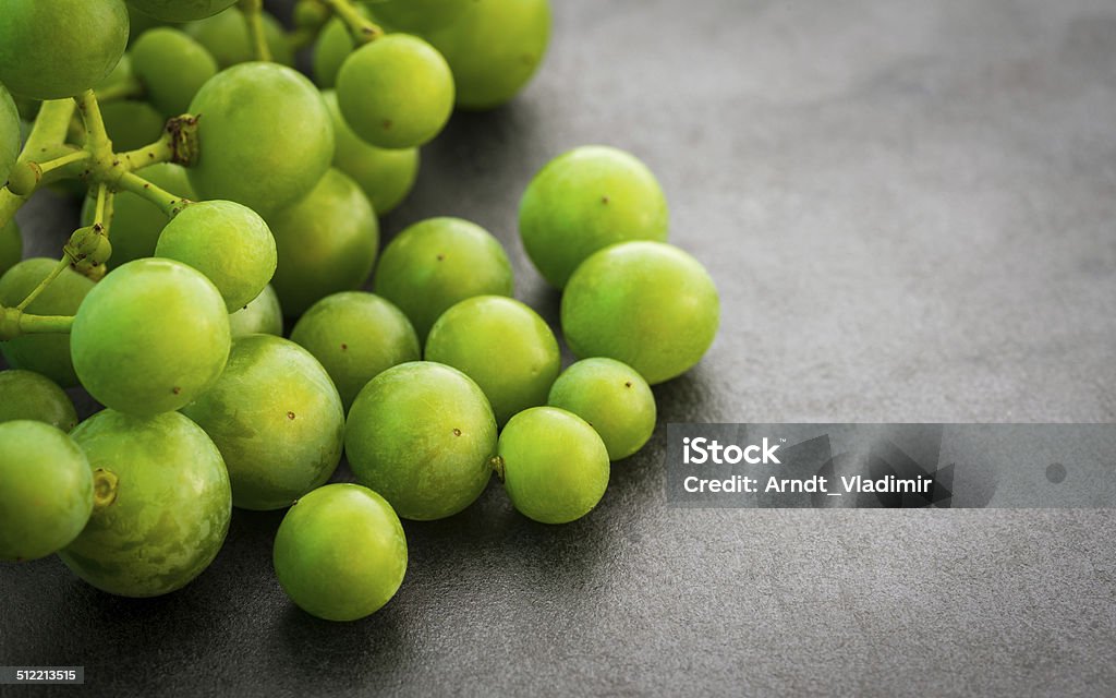 Unripe green grapes. 

Unripe green grapes on dark background. Selective focus with shallow depth of field.  Agriculture Stock Photo