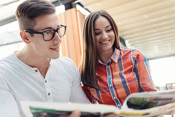 istock Young couple reading newspaper and drinking coffee in modern cafe 512213922