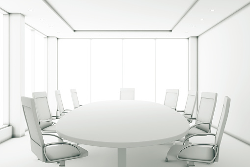 Completely white meeting room with a round table and large windows
