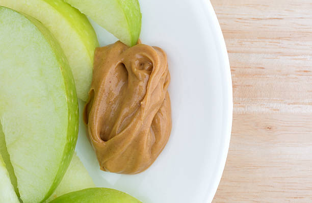 istock Green apple slices on dish with peanut butter table top 512214868