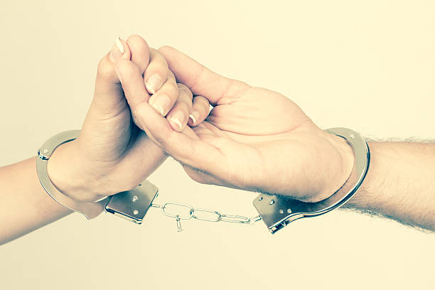 istock Man and woman's hands handcuffed together 512216067