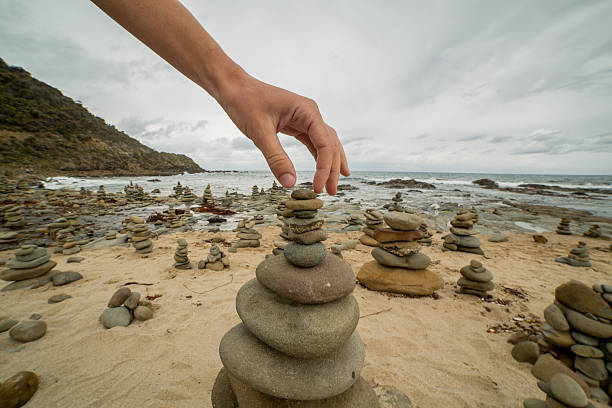 istock Person stacking last rock on pebble tower by the sea 512216766