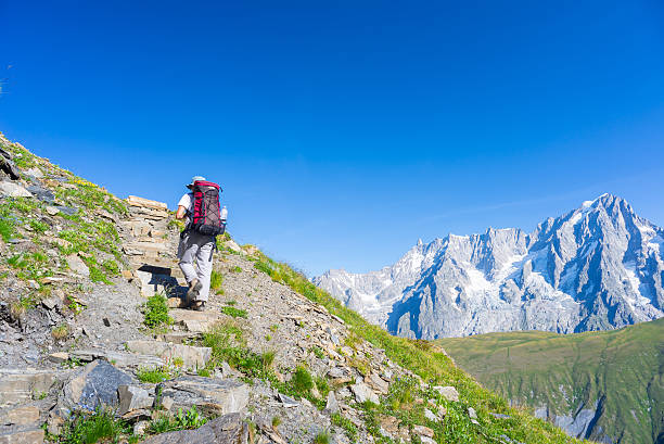 mochileiro caminhadas sobre os alpes, o majestoso monte branco em segundo plano - courmayeur european alps mont blanc mountain - fotografias e filmes do acervo