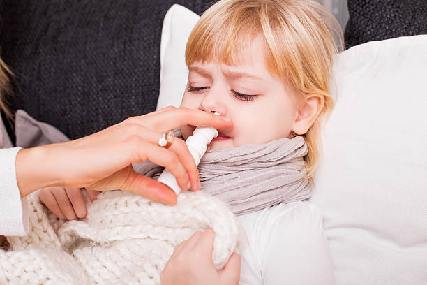 niño utilizando un medicamento para el tratamiento de frío - child human nose allergy spraying fotografías e imágenes de stock